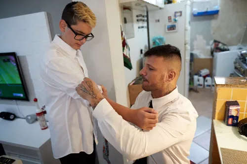 a father helping his son with his shirt sleeve