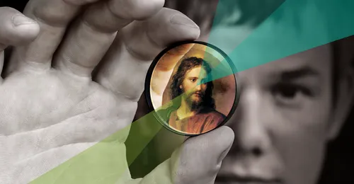 young man focusing on an image of Jesus Christ between his fingers