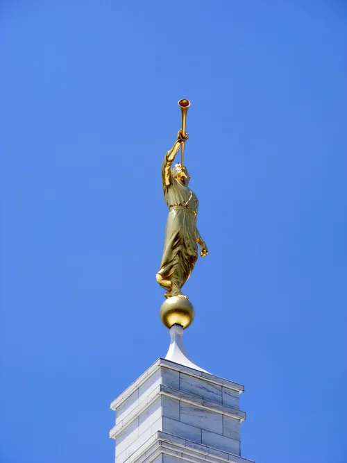 The angel Moroni statue seen atop the Raleigh North Carolina Temple on a clear day with a bright blue sky in the background.