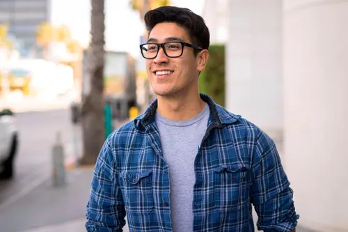 young adult man walking on street smiling