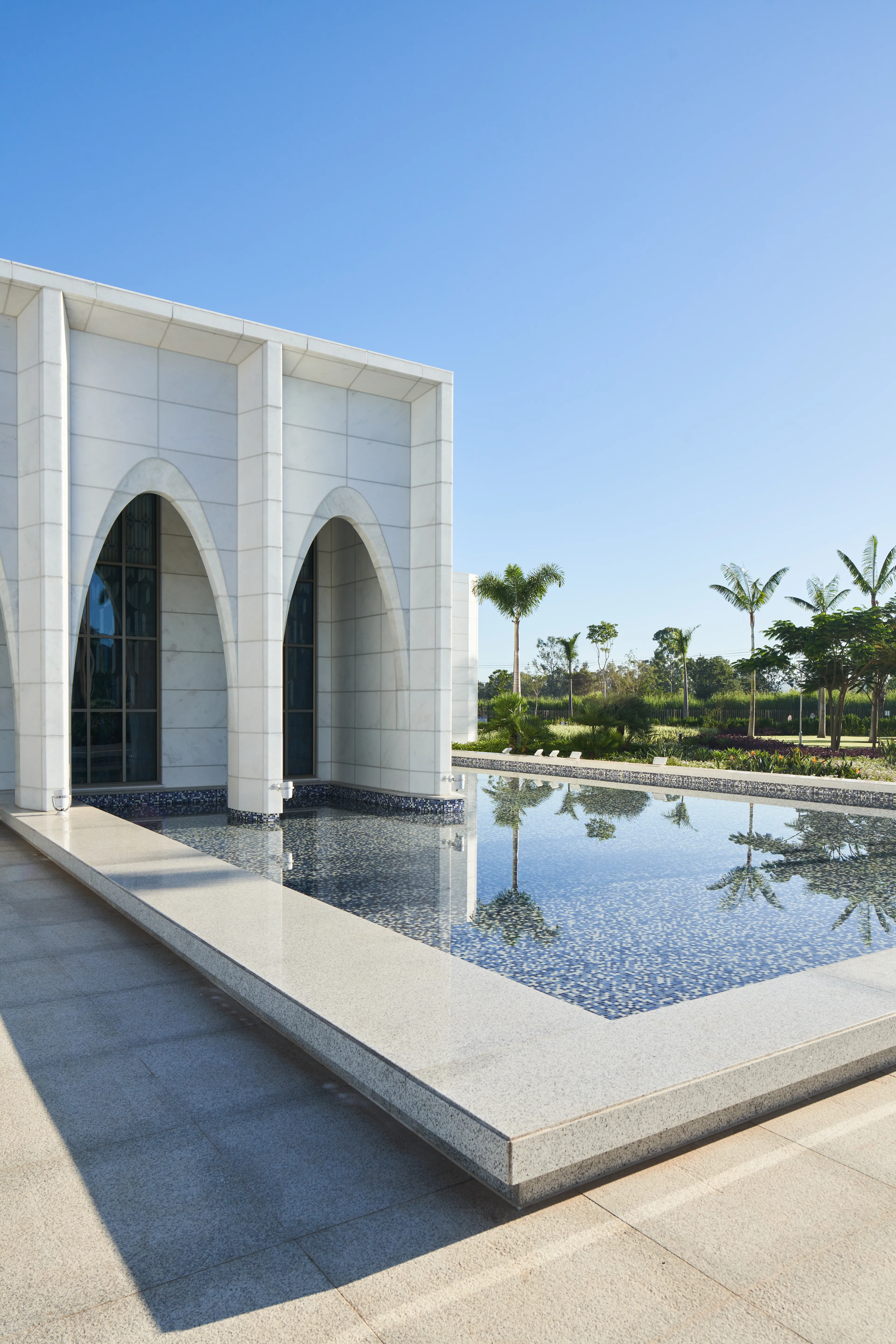 Exterior of the Brasilia Brazil Temple. It features the front of the temple, archways, and reflecting pools. Image was taken during the day.