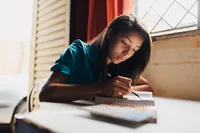 Two young women study the Bible while sitting on a bench