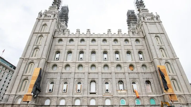 The Salt Lake Temple is under construction. Part of the temple has a tarp over the side and wooden support beams. 