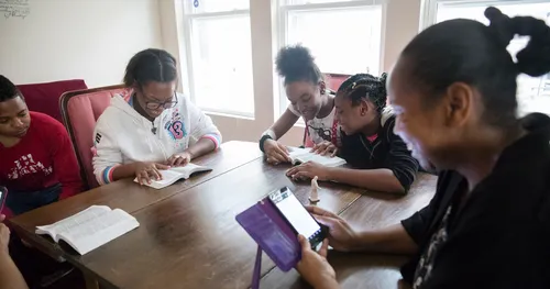 Family studies scriptures together with some using cellphones and others using books.