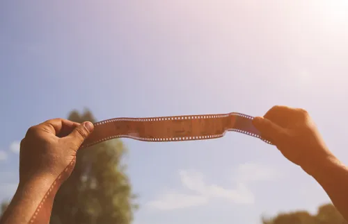 hands holding film strip up to the sky