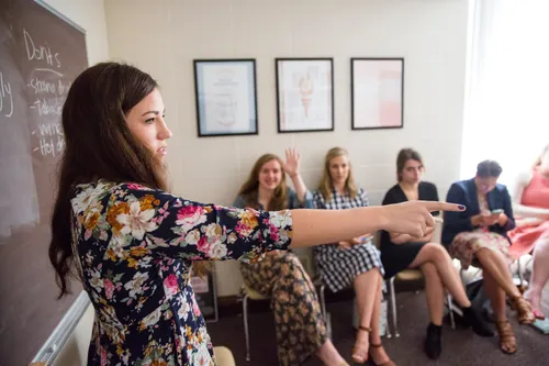 a woman points to somebody in the class during a lesson