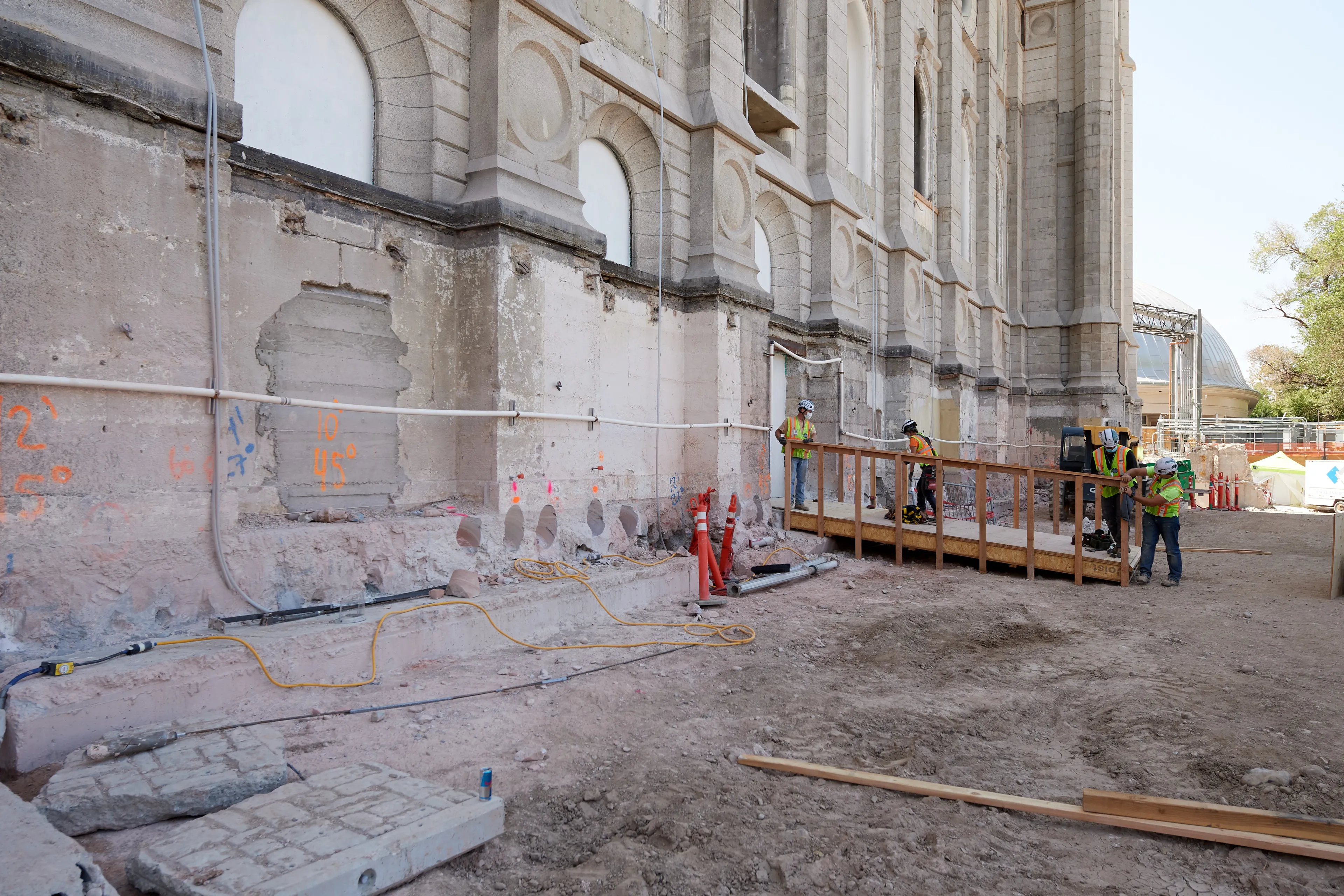 Construction on the Salt Lake Temple during September, 2020. Construction workers work on the site. Construction workers build a fence. 