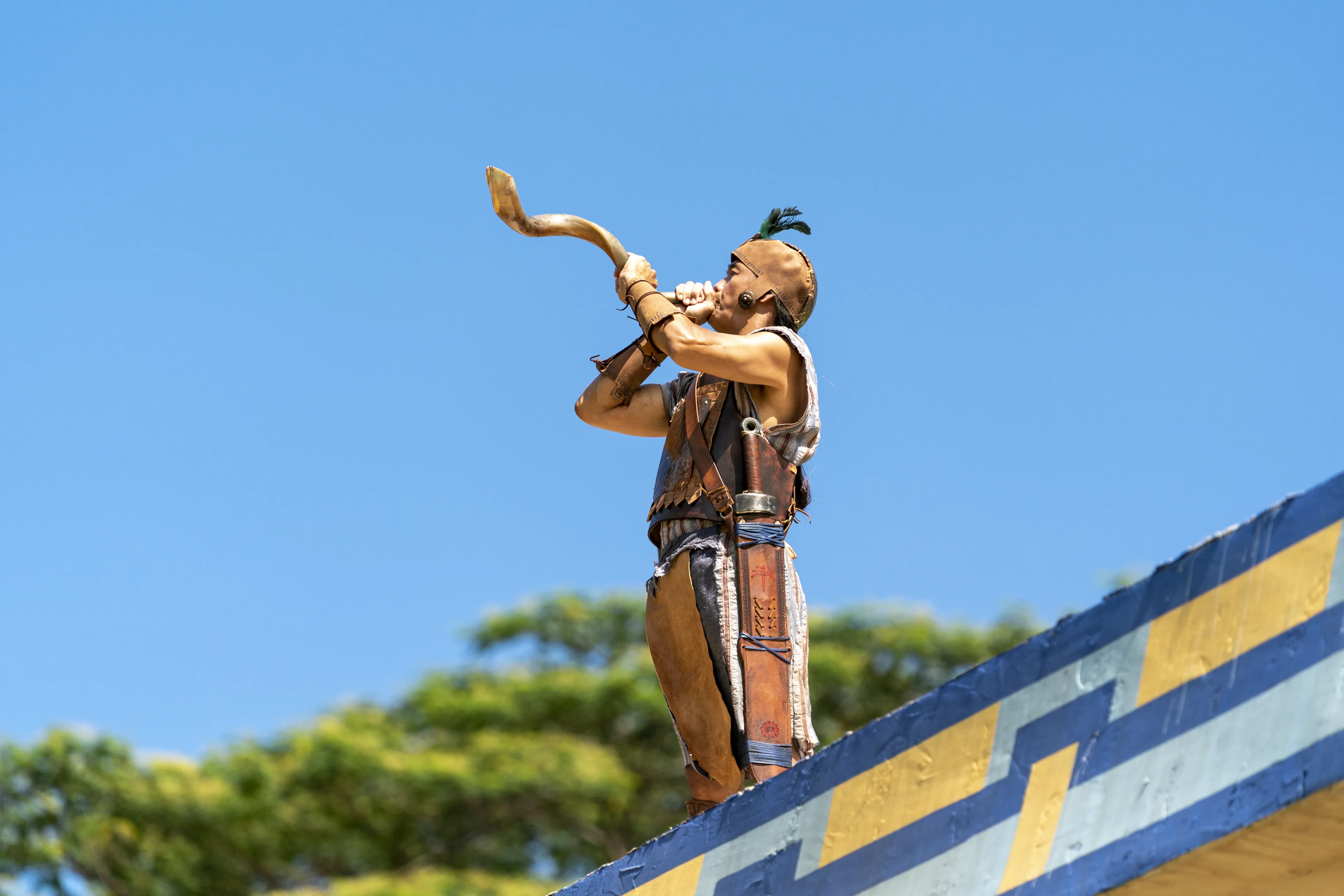 A man stands near the tower and blows a horn to call the people to hear King Benjamin in the Land of Zarahemla.