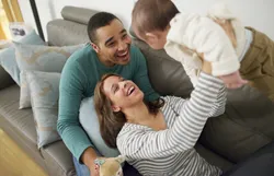 A couple plays with their baby in their house
