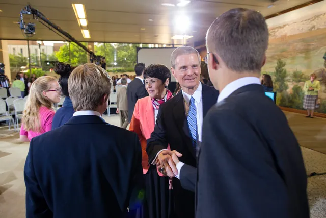 David Bednar and wife talking to youth and greeting them.