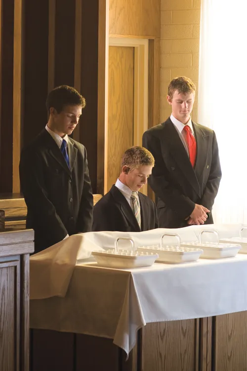 Three priests (one kneeling, two standing) while  the sacrament is being blessed.