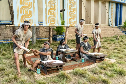 Scribes sit, taking notes of what King Benjamin is teaching. Runners take the parchment to the Nephite people in the Land of Zarahemla.