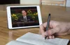 hand taking notes with tablet in background