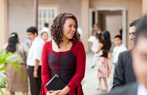 Church members leaving church, including a woman holding a set of scriptures