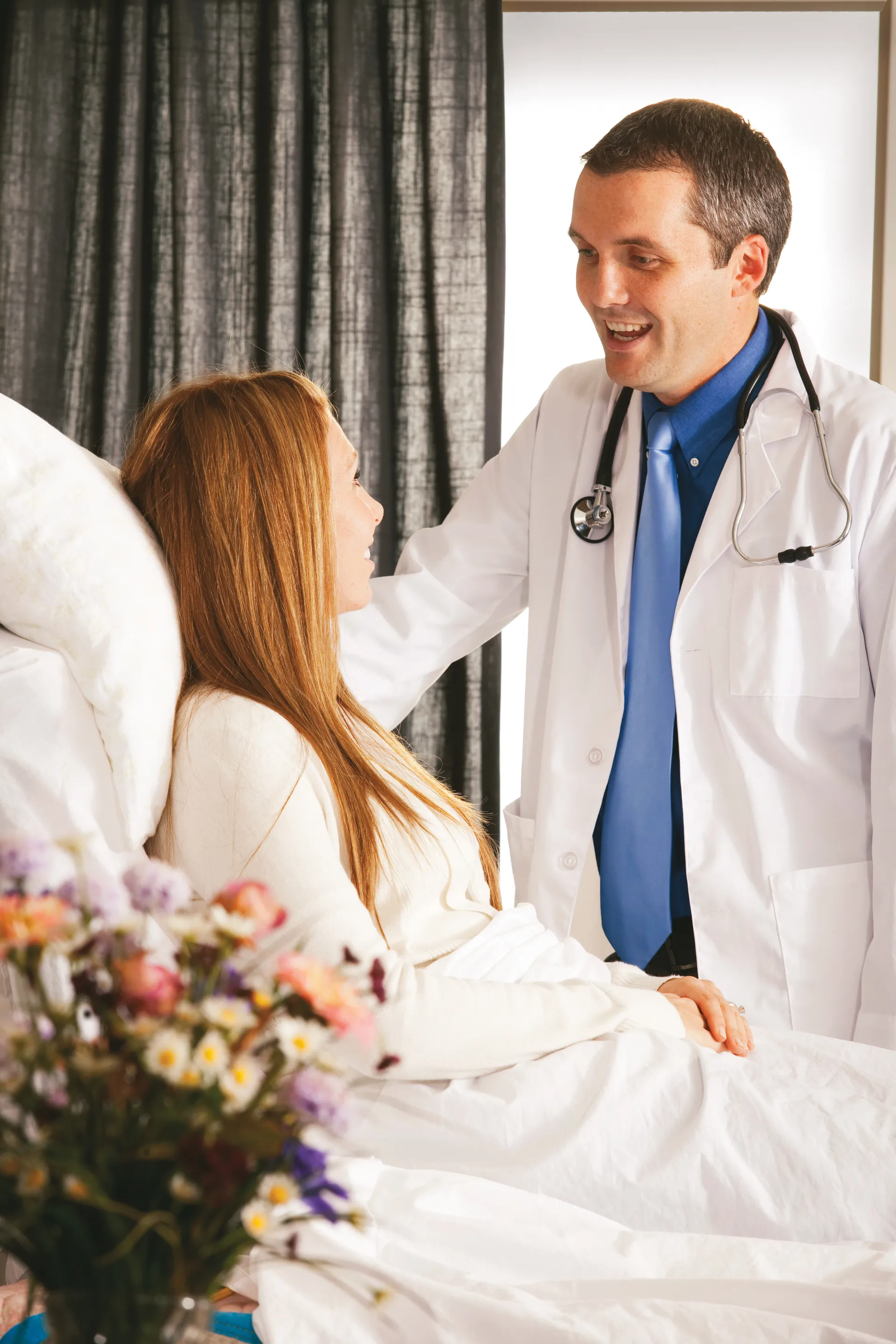 A doctor standing next to a patient in a hospital bed.