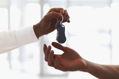 one hand giving a set of car keys to another hand