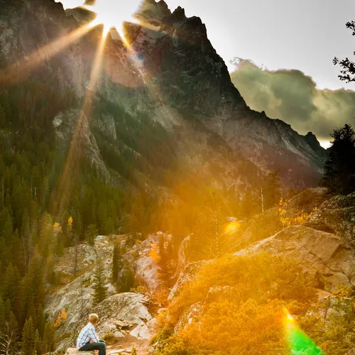 person sitting and looking up at mountain