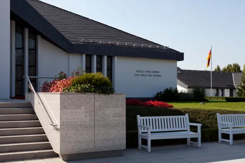 The entrance to the Freiberg Germany Temple, with large white benches in the courtyard and a German flag on the grounds.