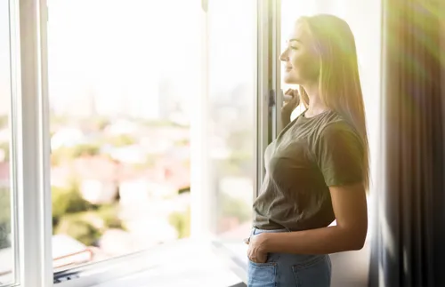 a woman faces the sunlight coming in from a window