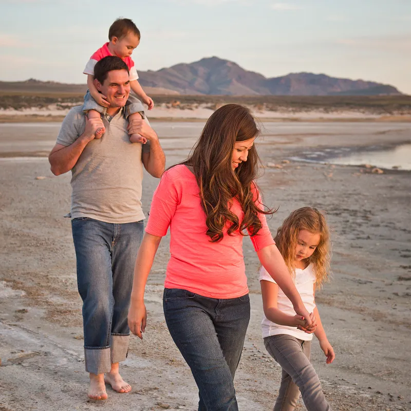 A young family walks down a beach with their two children