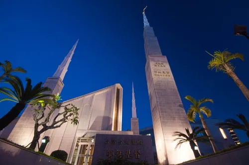 The front of the Taipei Taiwan Temple, with a view of the temple name sign and three spires, all lit up at night.