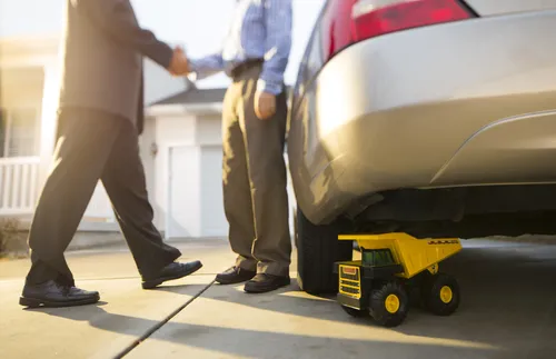 men shaking hands next to a car and toy truck