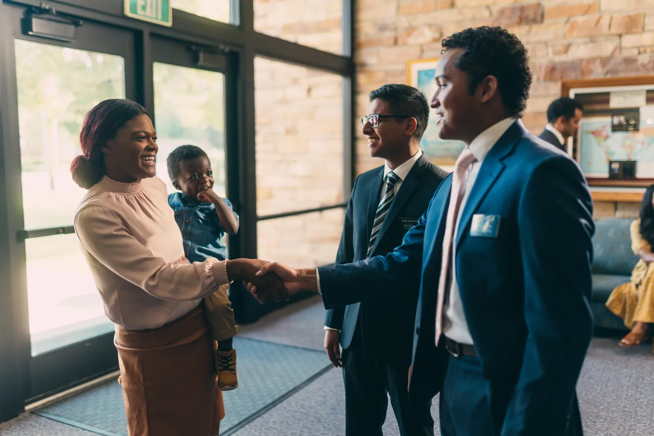 Missionaries greet a woman and her child at church