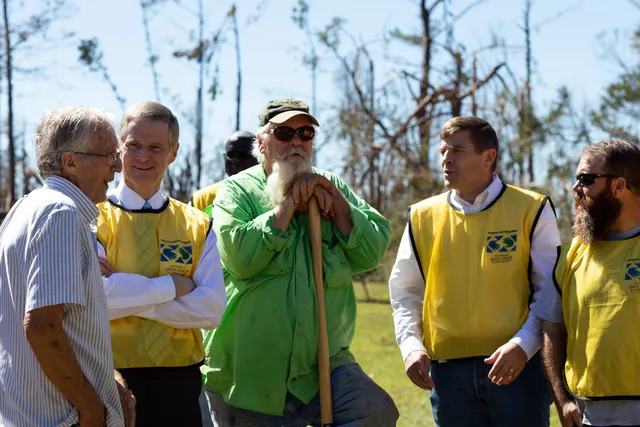 Elder David A. Bednar is outside. He is wearing a yellow Helping Hands vest. He is talking with other volunteers who are working. They are in Mariana, Florida on October 21, 2018.&nbsp;