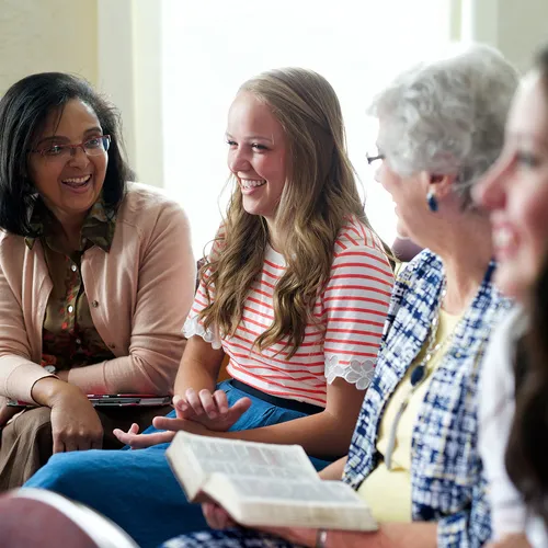 sisters sitting and smiling together in Relief Society