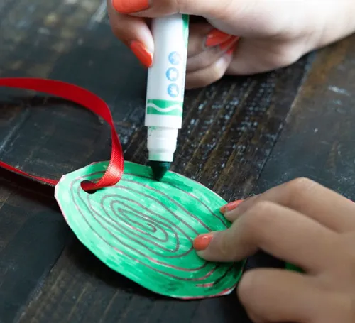 Hands coloring a Christmas ornament