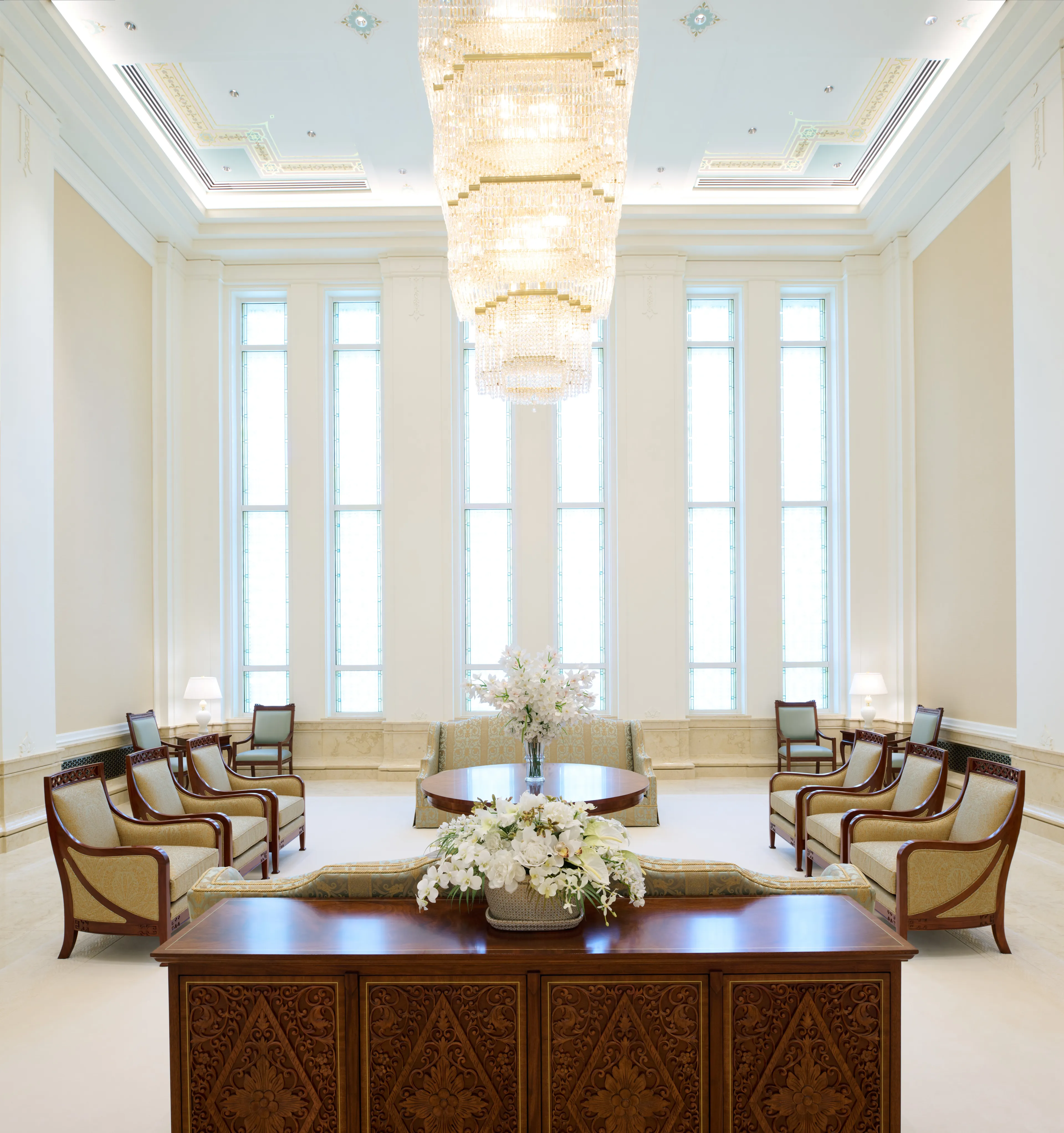 Interior image of the Bangkok Thailand Temple showing the Celestial Room. Image highlights a chandelier hanging from the center of the room with chairs and couches around.