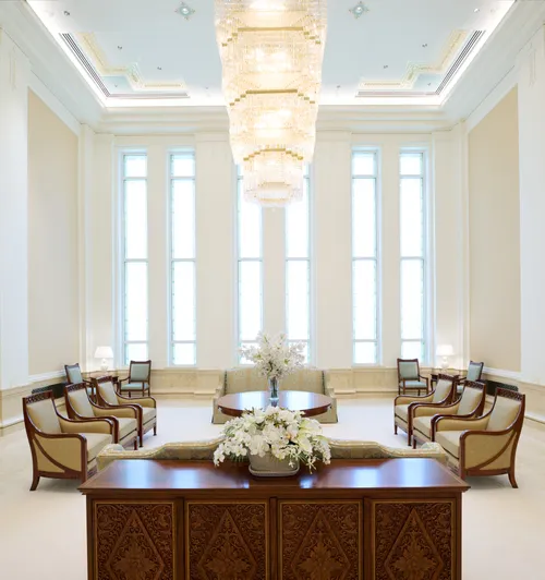 Interior image of the Bangkok Thailand Temple showing the Celestial Room. Image highlights a chandelier hanging from the center of the room with chairs and couches around.