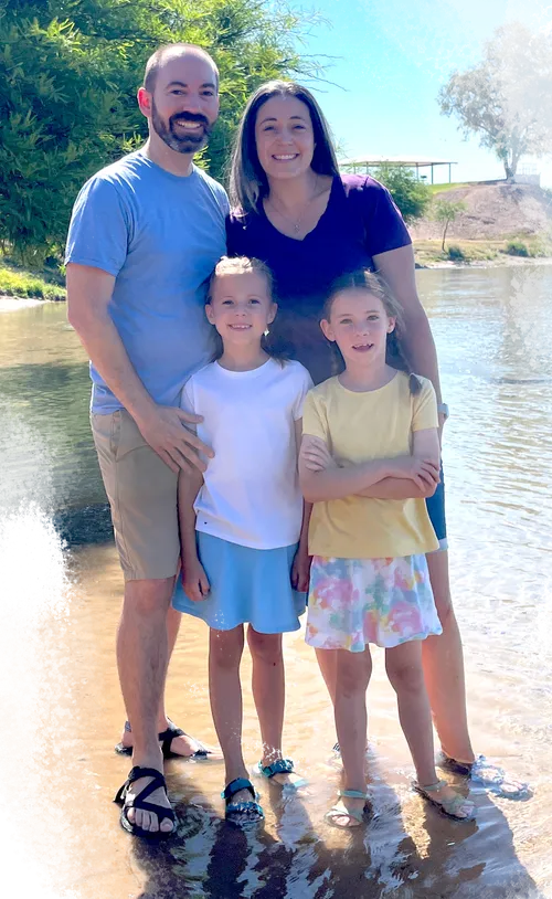 Girls standing in a river with their mom and dad