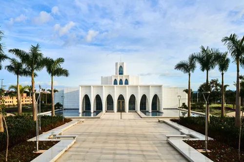 Exterior of the Brasilia Brazil Temple. It features the front of the temple, the entrance area, and trees nearby. Image was taken during the day.