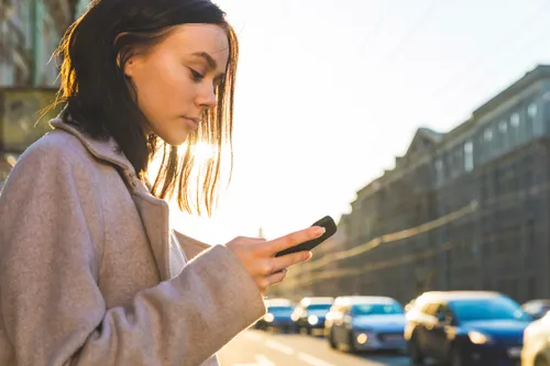 woman holding a phone on a city street