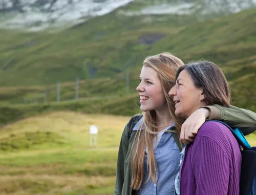 A young woman and an older woman standing together on a mountain.