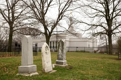 Headstones in a cemetery, with the Winter Quarters Nebraska Temple in the background.