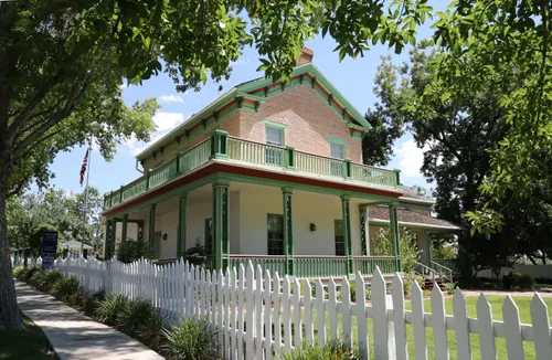 A view of the Brigham Young winter home seen from the sidewalk, with green trees in the foreground.