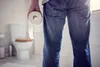 person holding toilet paper and looking at toilet