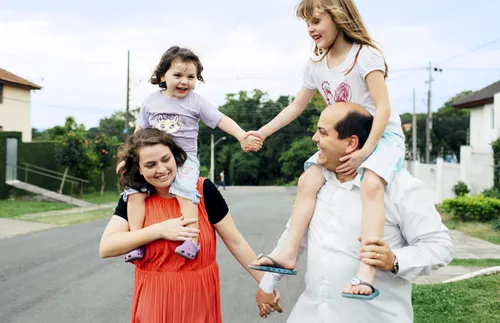 parents carrying children on shoulders