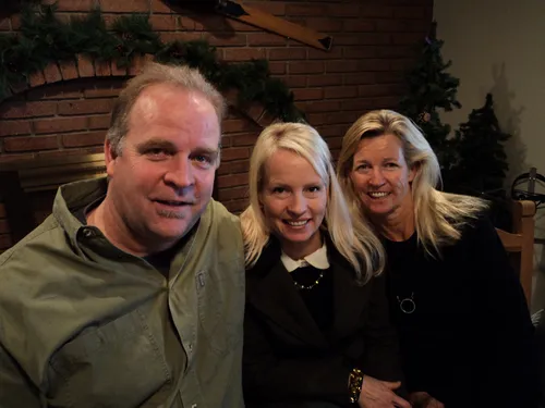 A man and two women in front of a fireplace.