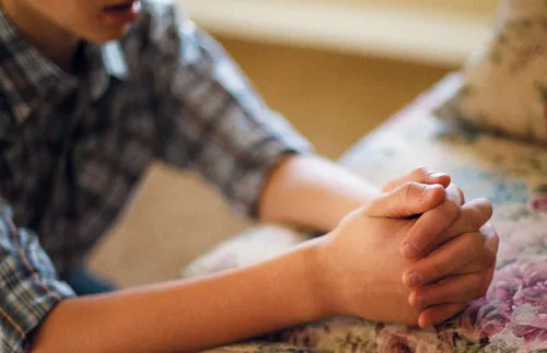 a young adult kneeling and praying
