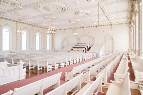 Interior image of the Manti Utah Temple. The image features the Assembly Room. There are pews throughout the room and wood details across the ceiling.