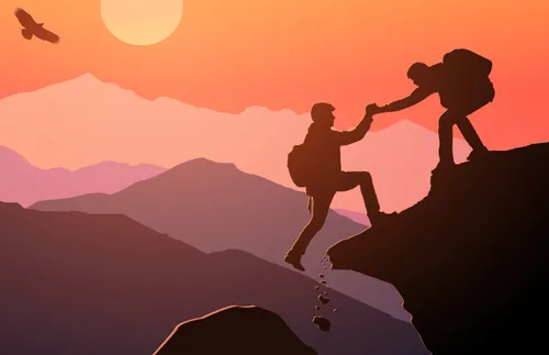 one person helping another climb a mountain