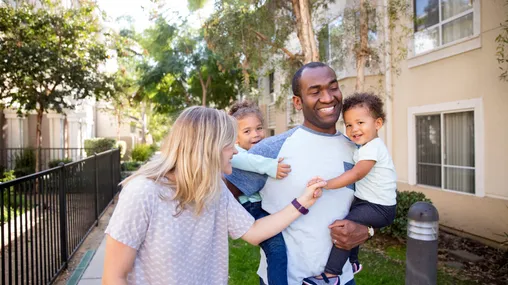 A family enjoys their time together as they walk down a sidewalk.