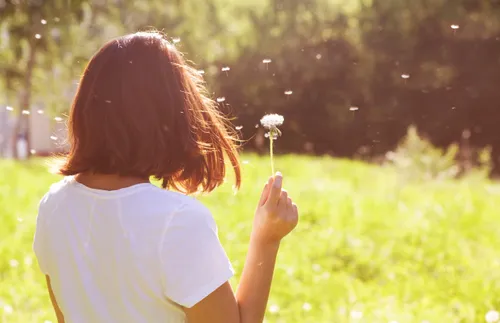 Woman holding a dandelion in a field