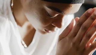A women with her hands together, she is praying