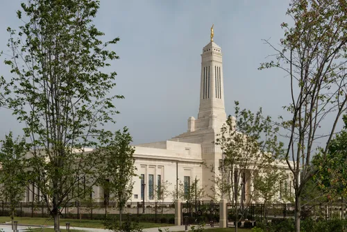 The trees and fence in front of the Indianapolis Indiana Temple on a cloudy day.