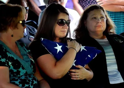A woman (Amanda Blount) holding an American flag and crying.