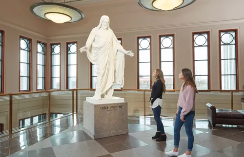 two young adults looking up at a Christus statute